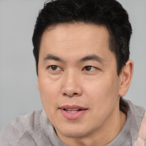 Joyful asian adult male with short  brown hair and brown eyes