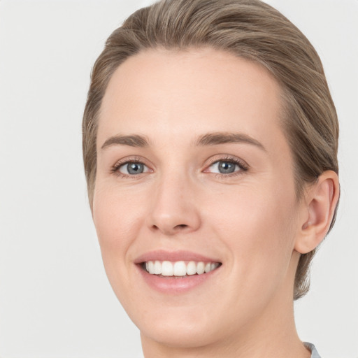 Joyful white young-adult female with medium  brown hair and grey eyes