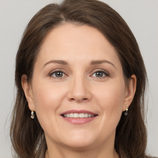 Joyful white adult female with long  brown hair and grey eyes