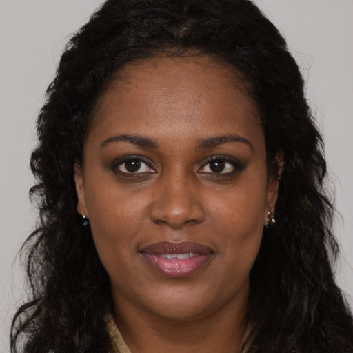 Joyful black adult female with long  brown hair and brown eyes