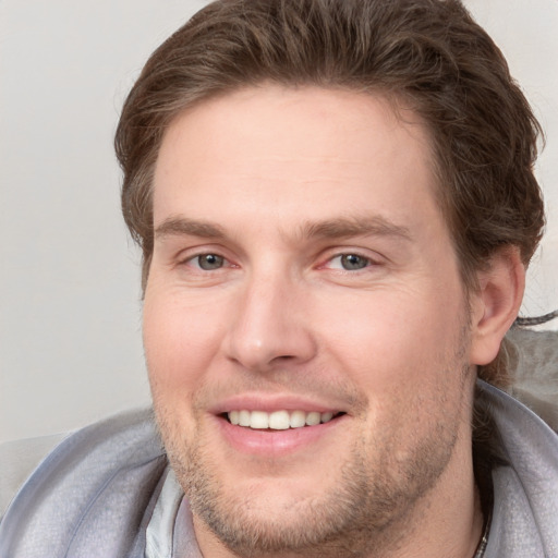 Joyful white young-adult male with short  brown hair and grey eyes