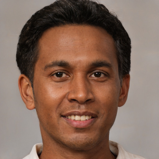 Joyful black young-adult male with short  brown hair and brown eyes