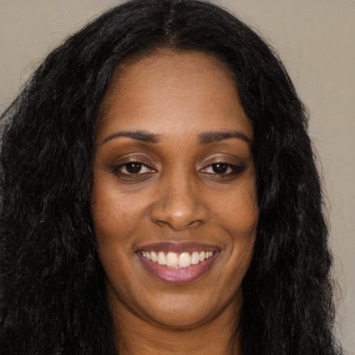Joyful black young-adult female with long  black hair and brown eyes