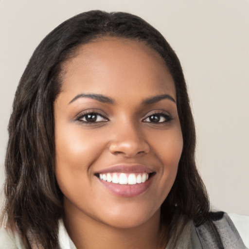 Joyful black young-adult female with long  brown hair and brown eyes