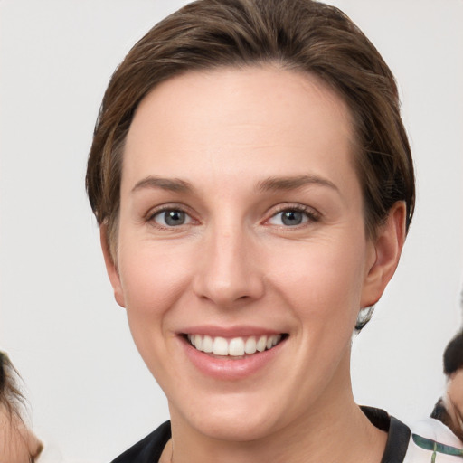 Joyful white young-adult female with short  brown hair and grey eyes