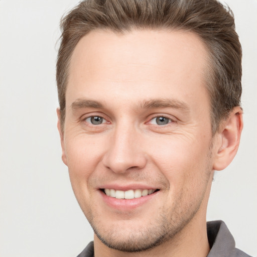 Joyful white young-adult male with short  brown hair and grey eyes