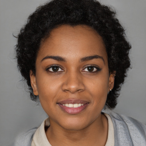 Joyful black young-adult female with short  black hair and brown eyes