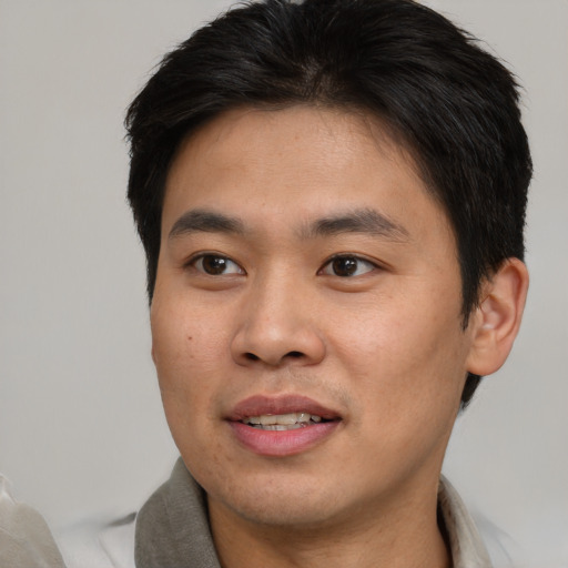 Joyful asian young-adult male with short  brown hair and brown eyes