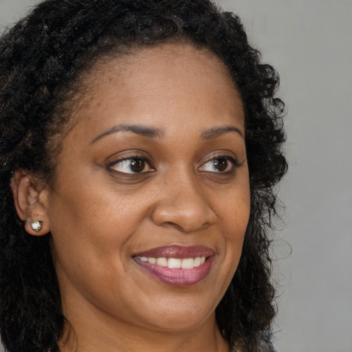 Joyful black young-adult female with long  brown hair and brown eyes
