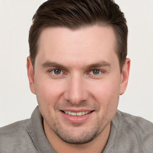 Joyful white young-adult male with short  brown hair and grey eyes