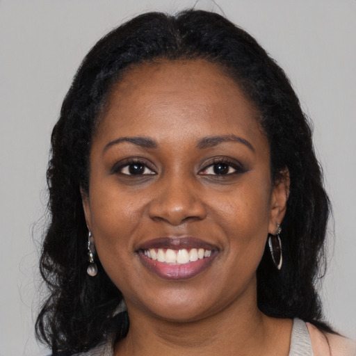 Joyful black young-adult female with long  black hair and brown eyes