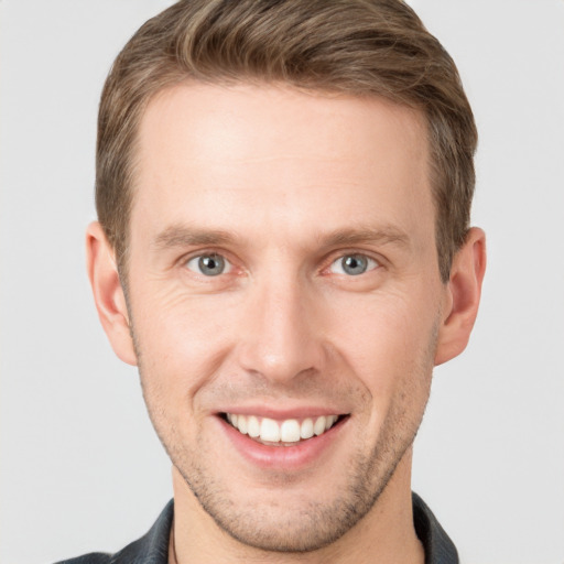 Joyful white young-adult male with short  brown hair and grey eyes