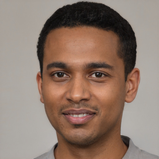 Joyful black young-adult male with short  black hair and brown eyes