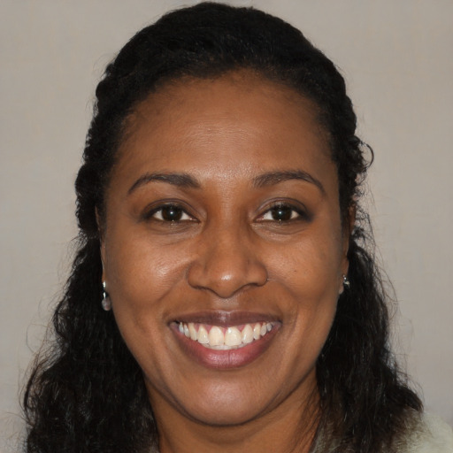 Joyful black adult female with long  brown hair and brown eyes