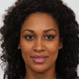 Joyful black young-adult female with long  brown hair and brown eyes