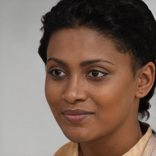 Joyful black young-adult female with short  black hair and brown eyes