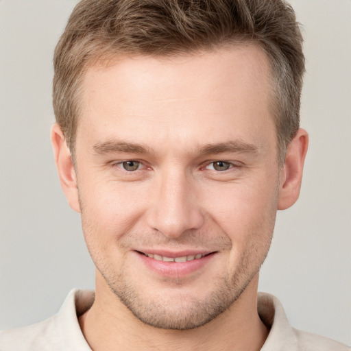 Joyful white young-adult male with short  brown hair and grey eyes