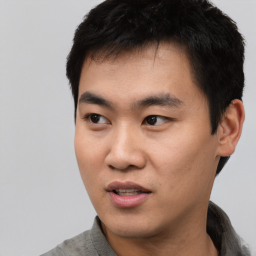 Joyful asian young-adult male with short  black hair and brown eyes