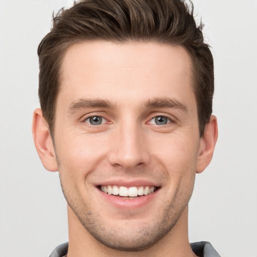 Joyful white young-adult male with short  brown hair and grey eyes