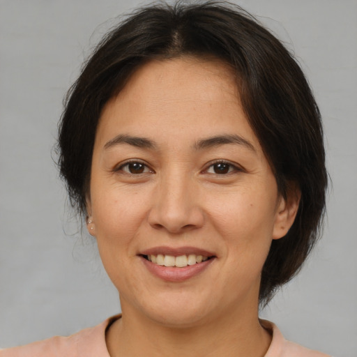 Joyful asian adult female with medium  brown hair and brown eyes