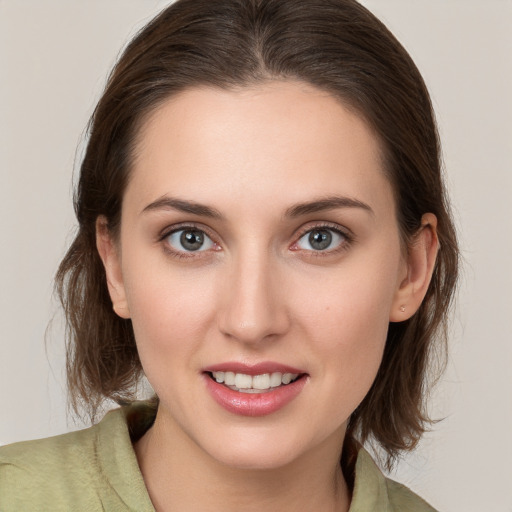 Joyful white young-adult female with medium  brown hair and grey eyes