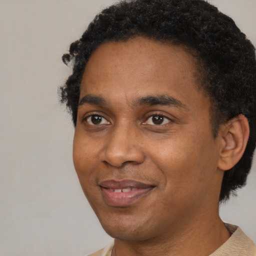 Joyful black young-adult male with short  black hair and brown eyes