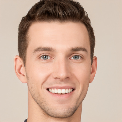 Joyful white young-adult male with short  brown hair and grey eyes