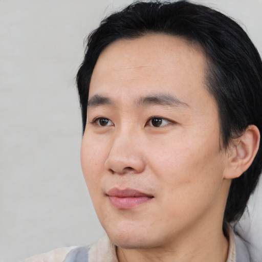 Joyful asian young-adult male with medium  black hair and brown eyes
