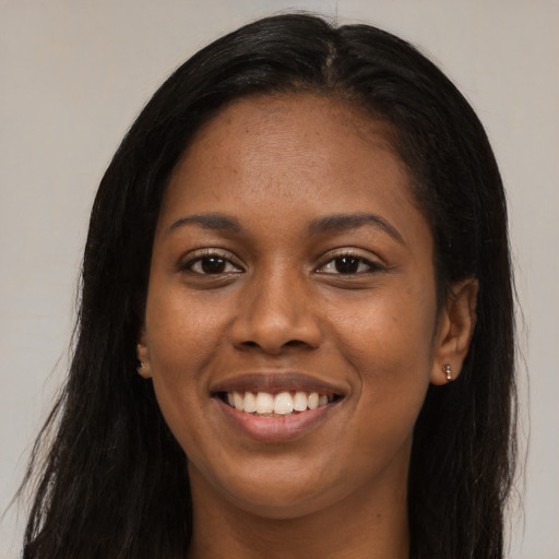 Joyful black young-adult female with long  black hair and brown eyes