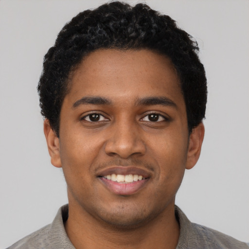 Joyful black young-adult male with short  black hair and brown eyes