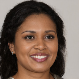 Joyful black young-adult female with long  brown hair and brown eyes