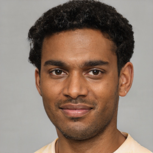 Joyful black young-adult male with short  brown hair and brown eyes