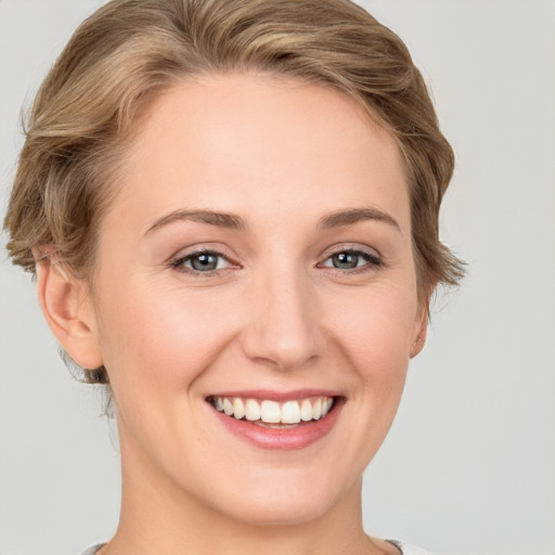 Joyful white young-adult female with medium  brown hair and grey eyes