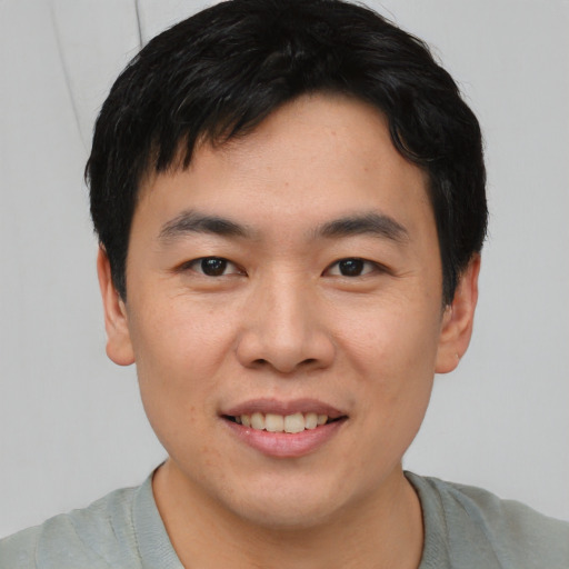 Joyful asian young-adult male with short  brown hair and brown eyes