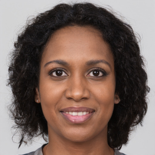 Joyful black young-adult female with long  brown hair and brown eyes