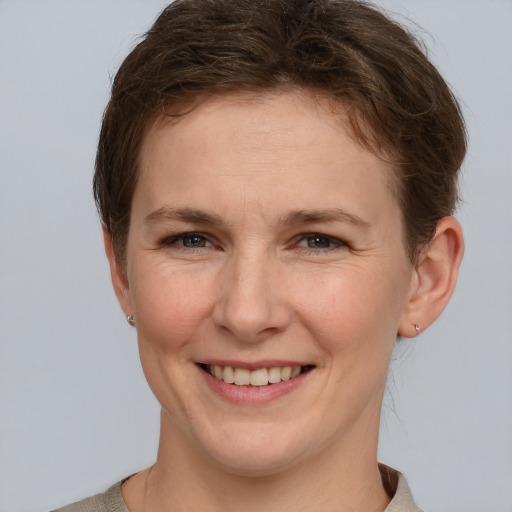 Joyful white young-adult female with short  brown hair and grey eyes