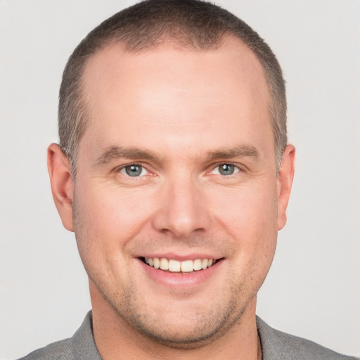 Joyful white young-adult male with short  brown hair and grey eyes