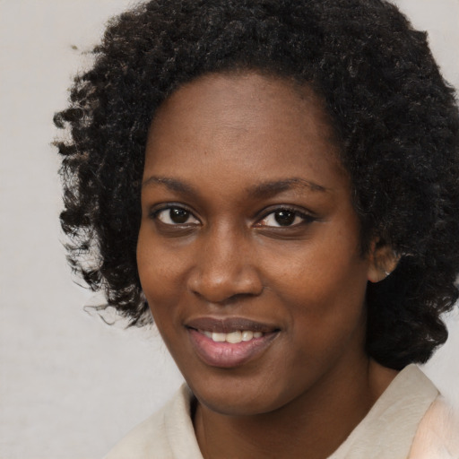 Joyful black young-adult female with short  black hair and brown eyes