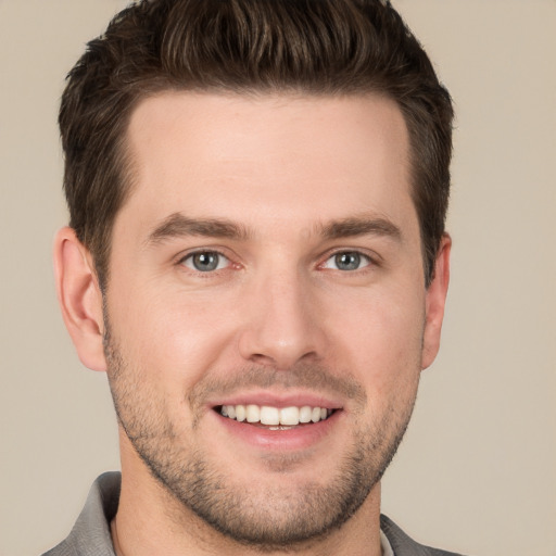 Joyful white young-adult male with short  brown hair and grey eyes