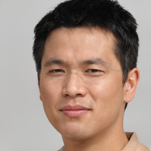 Joyful asian young-adult male with short  brown hair and brown eyes
