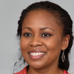 Joyful black young-adult female with long  brown hair and brown eyes