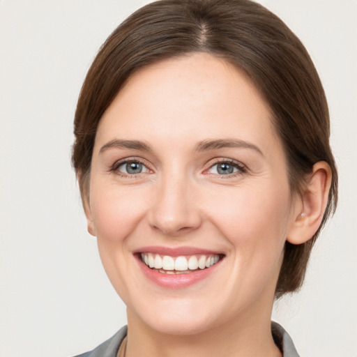 Joyful white young-adult female with medium  brown hair and grey eyes