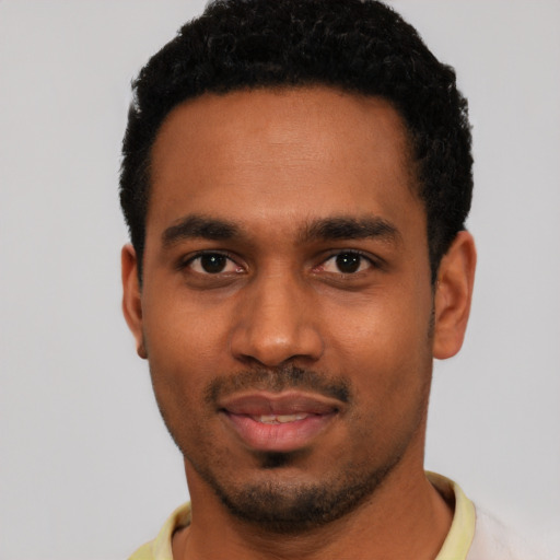 Joyful black young-adult male with short  black hair and brown eyes