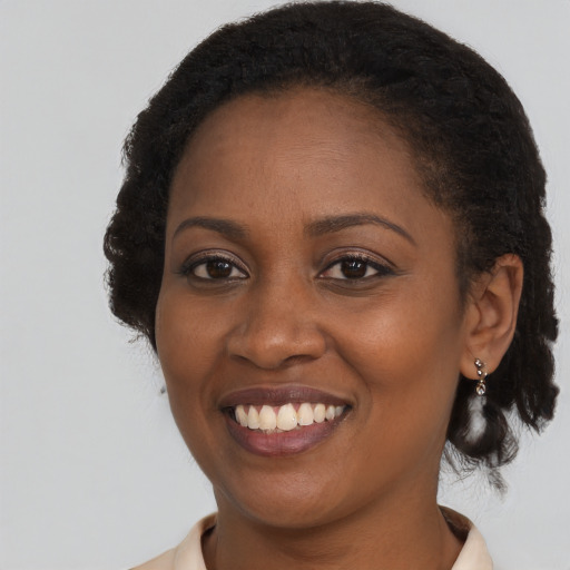 Joyful black young-adult female with long  brown hair and brown eyes