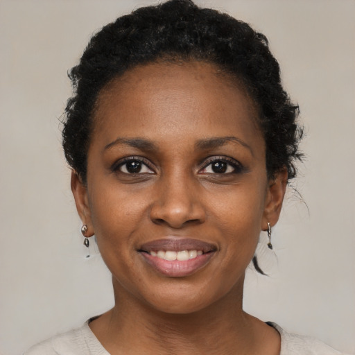 Joyful black young-adult female with short  black hair and brown eyes