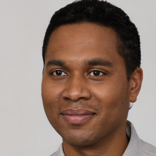 Joyful black young-adult male with short  black hair and brown eyes