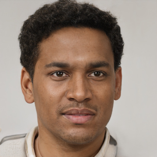 Joyful black young-adult male with short  brown hair and brown eyes