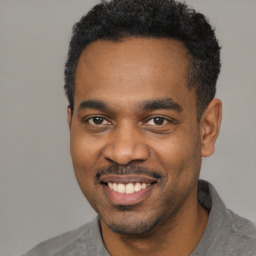 Joyful black young-adult male with short  black hair and brown eyes