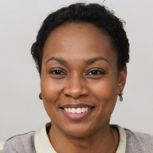 Joyful black young-adult female with short  black hair and brown eyes