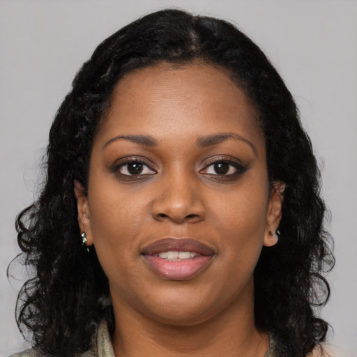 Joyful black young-adult female with long  black hair and brown eyes